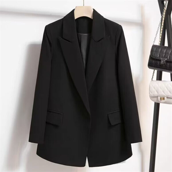 Black blazer hanging on a wooden hanger.