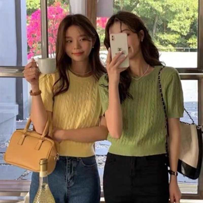 Two women smiling, holding coffee and phone.