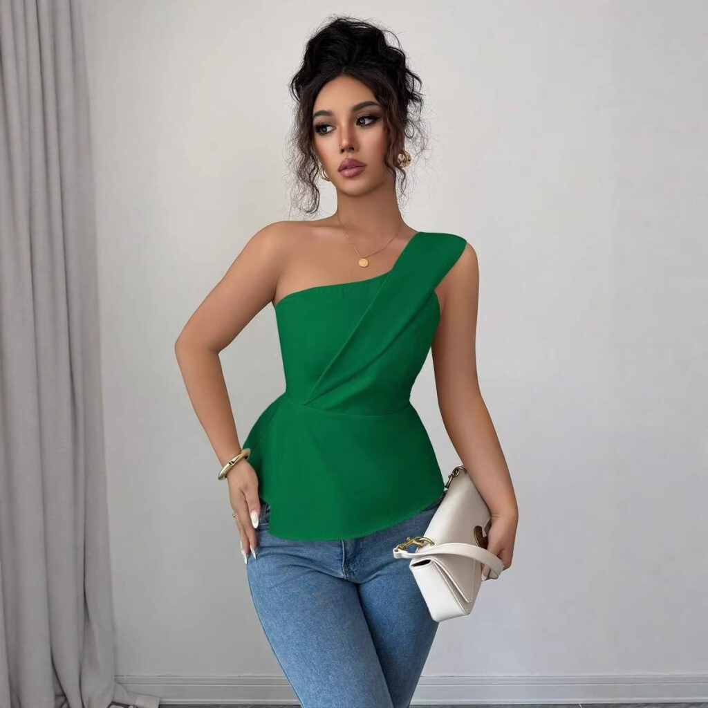 Woman in green top and jeans posing.