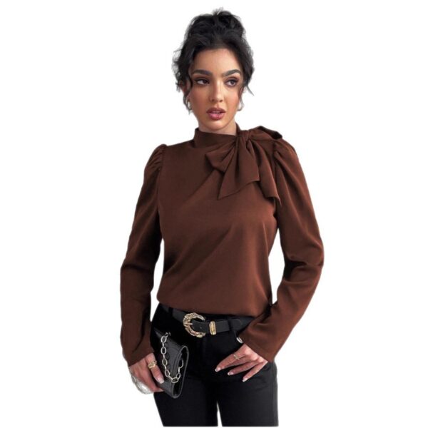 Woman wearing brown blouse with bow detail.