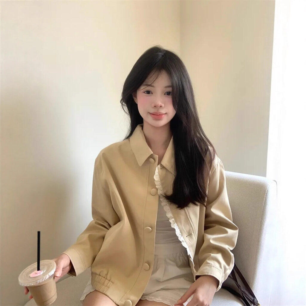 Woman sitting, holding iced coffee drink.