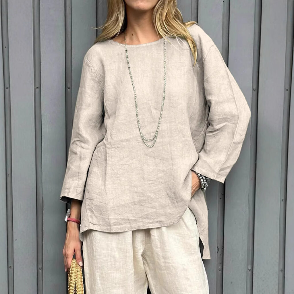 Woman in beige outfit against gray backdrop.