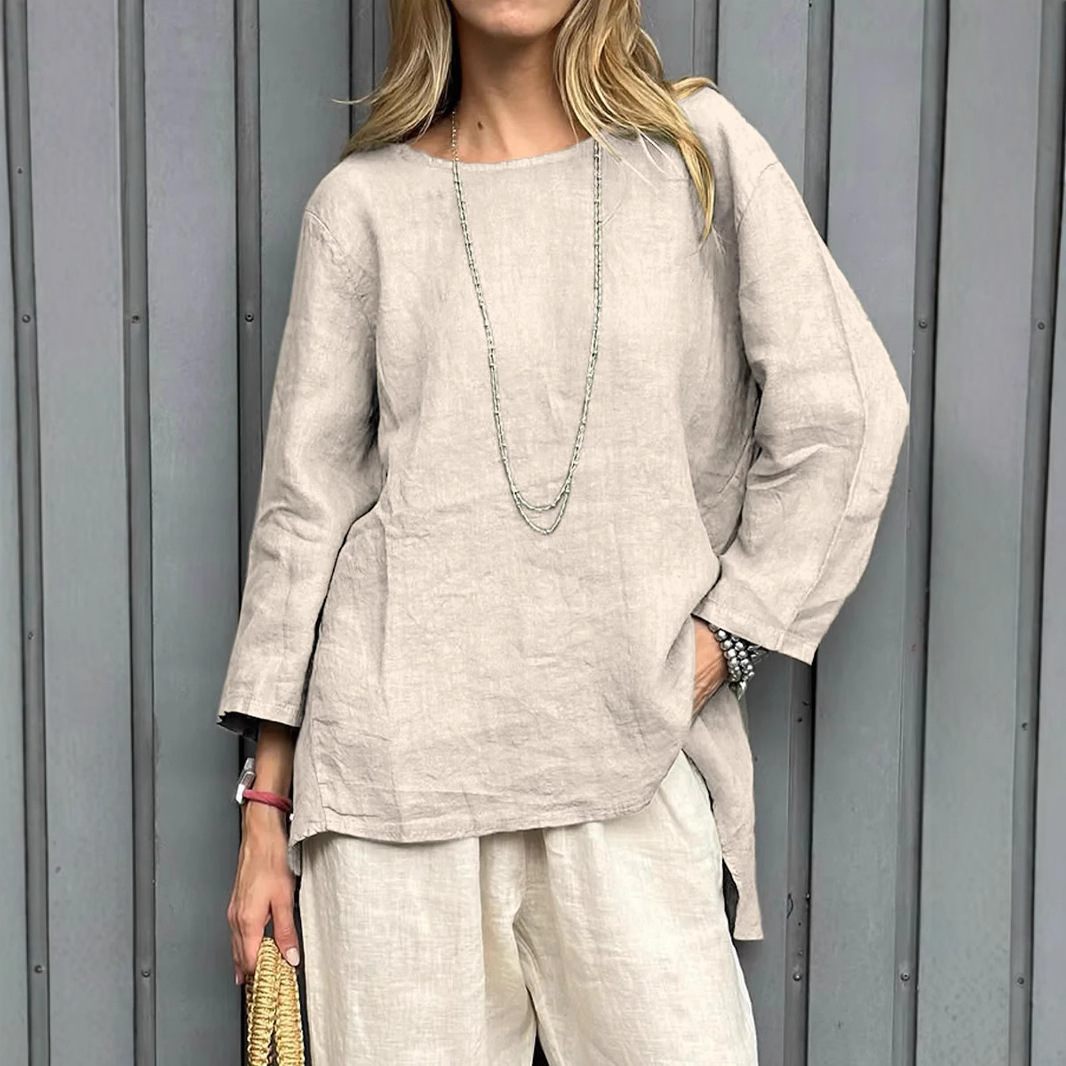 Woman wearing beige outfit, standing by wall.
