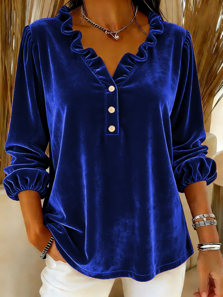 Woman wearing blue velvet blouse with ruffles.
