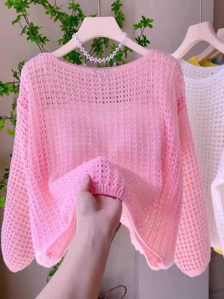 Pink knitted sweater on a hanger display.