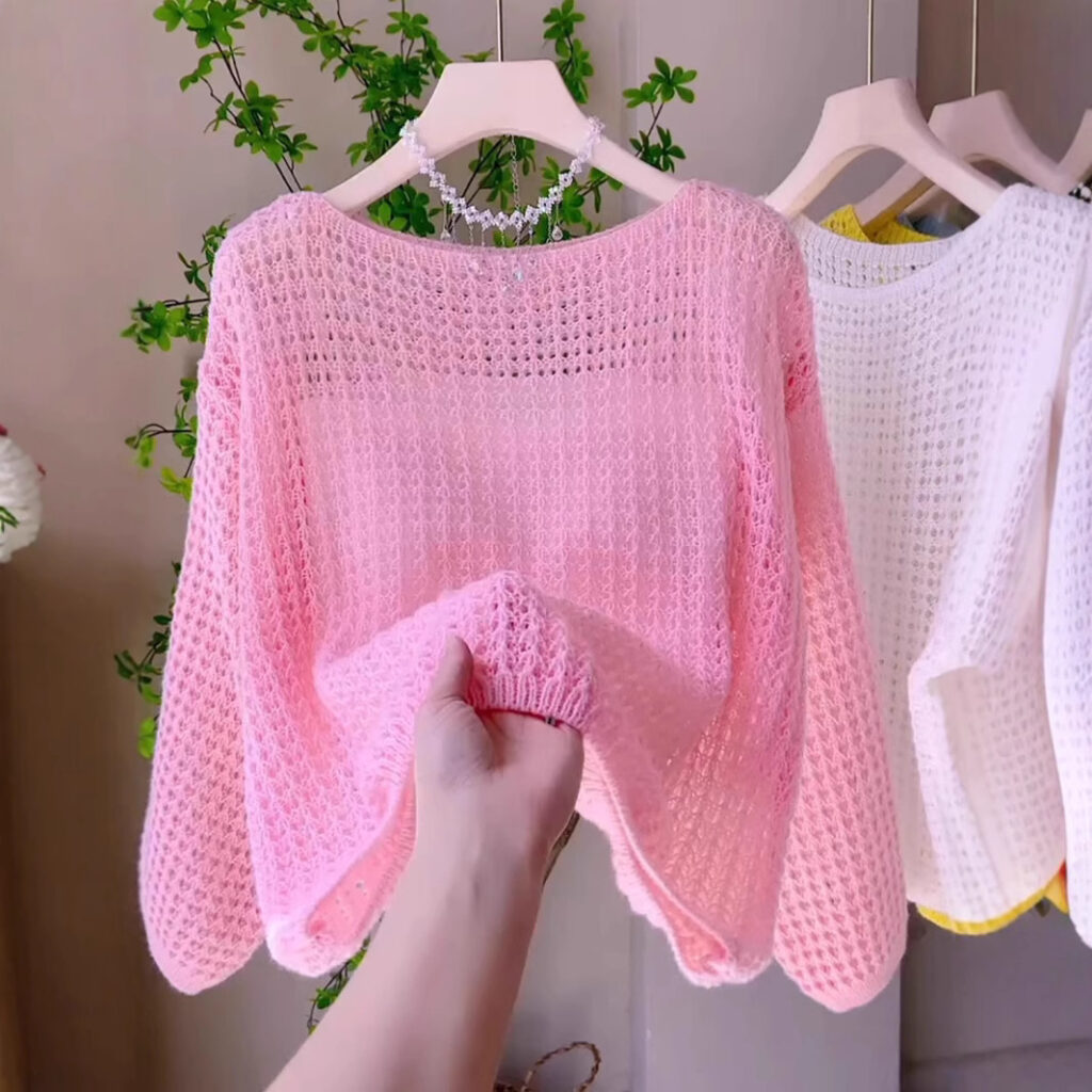 Hand holding pink knitted sweater.