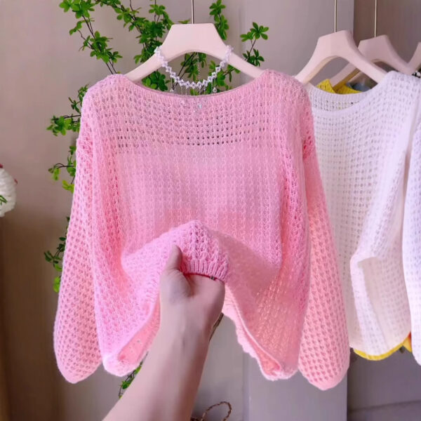 Hand holding pink knitted sweater.
