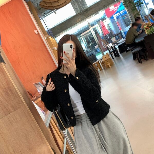 Person taking a mirror selfie in a casual outfit inside a cafe.