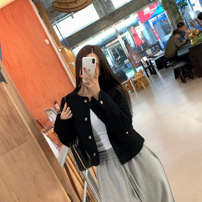Person taking a mirror selfie in a casual outfit inside a cafe.