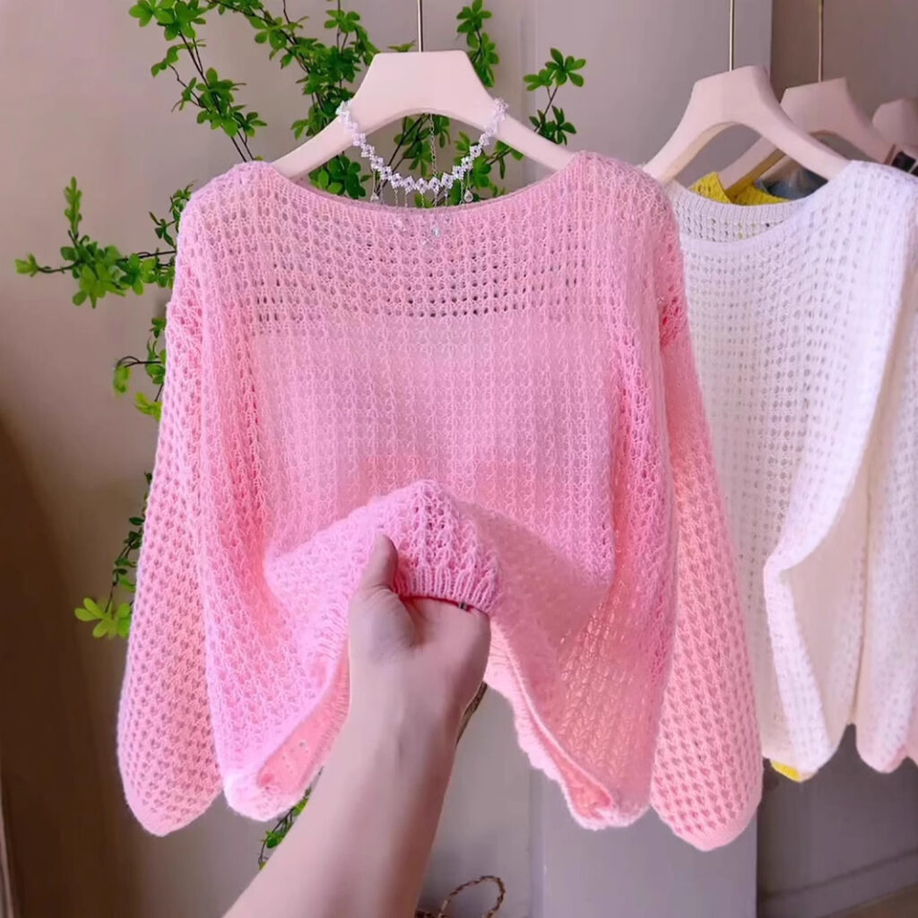 Hand holding pink knit sweater.
