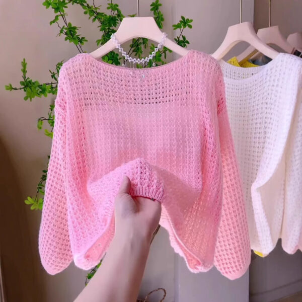 Hand holding pink knit sweater.