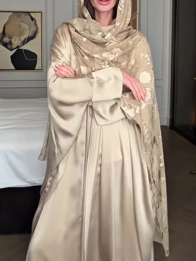 Woman in elegant embroidered beige outfit.