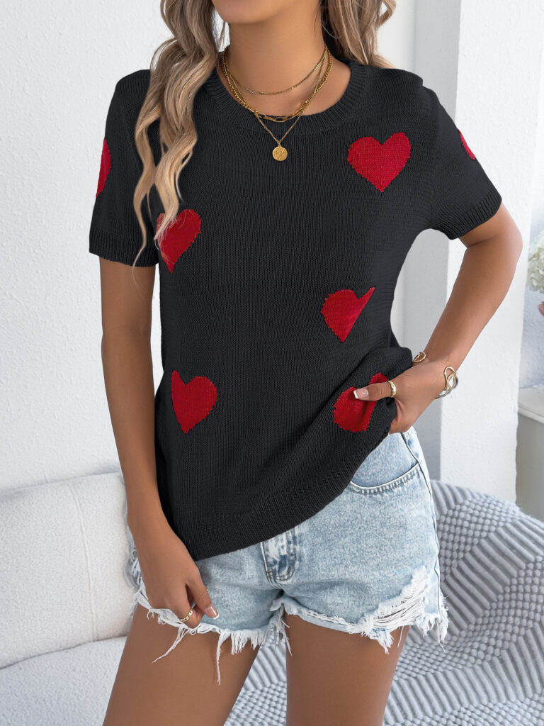 Woman in heart sweater and denim shorts.