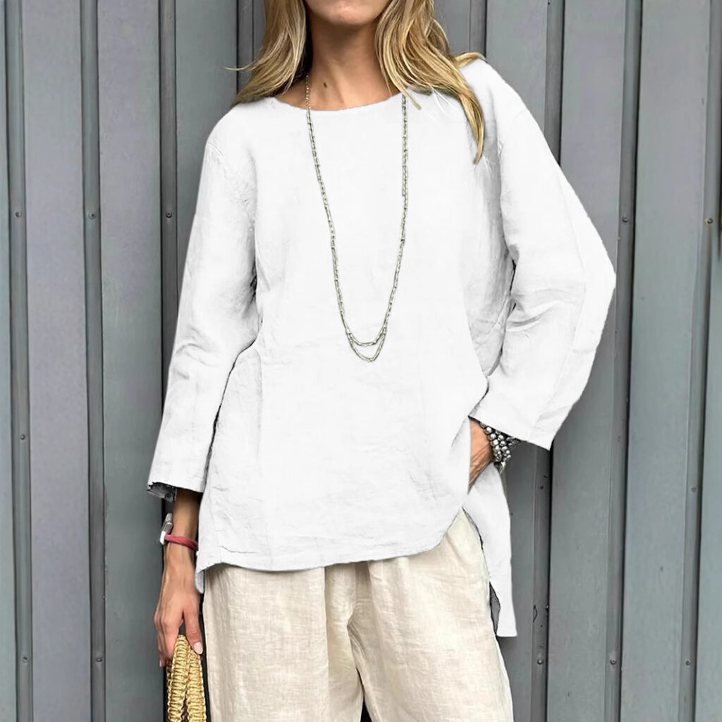 Woman in white outfit against gray wall.