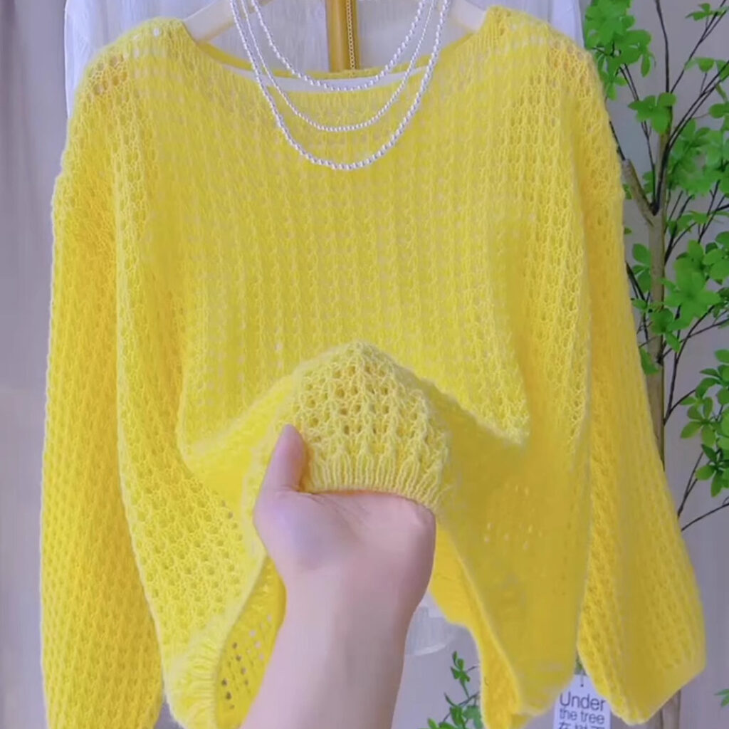 Hand holding yellow knitted sweater.