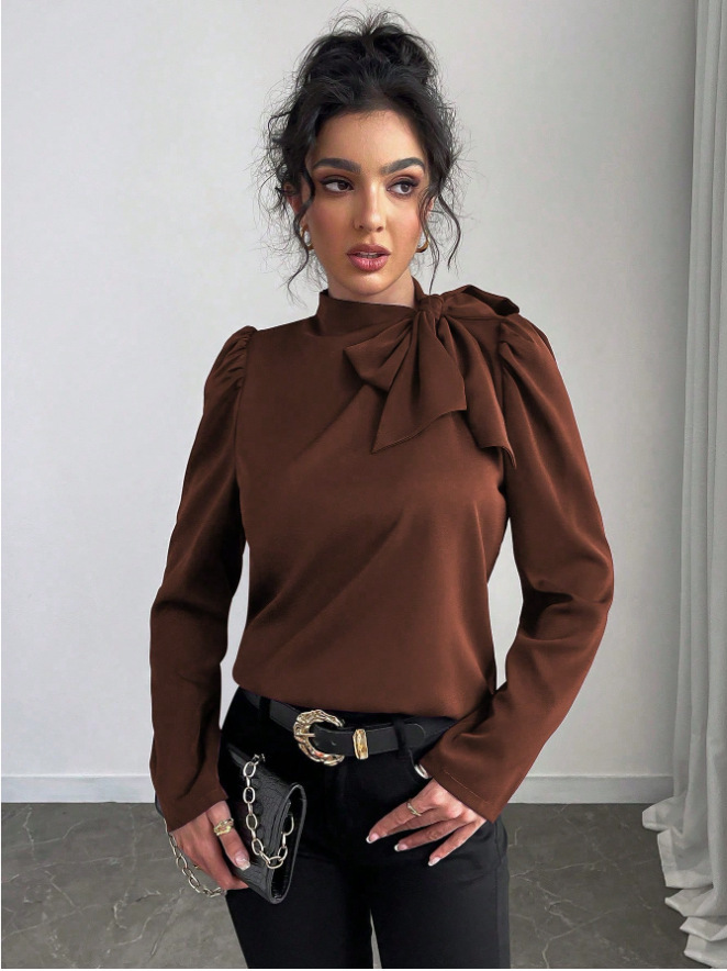 Woman in brown top with bow detail.