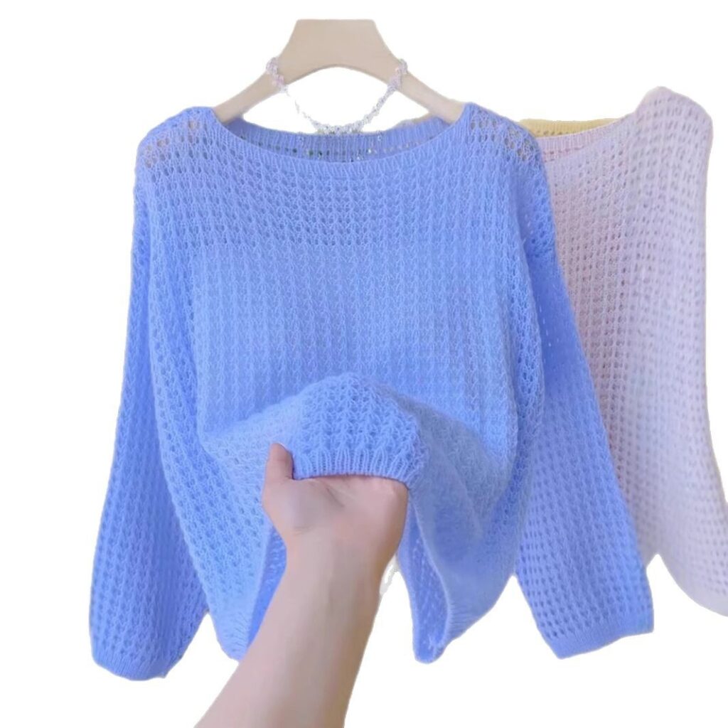 Hand holding light blue knitted sweater.