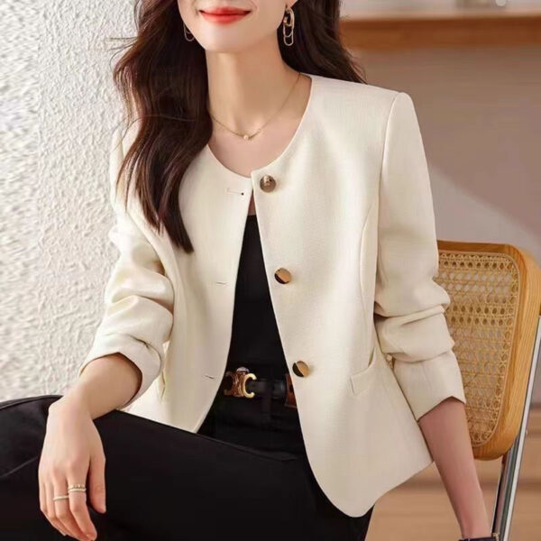 Woman in white blazer sitting on chair.