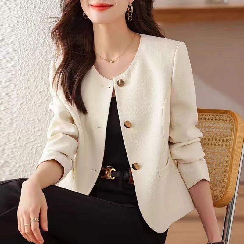 Woman in white blazer sitting on chair.
