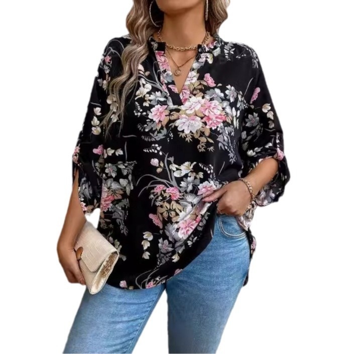 Woman in floral blouse holding a clutch.