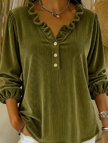 Woman in green ruffled blouse, hand in pocket.