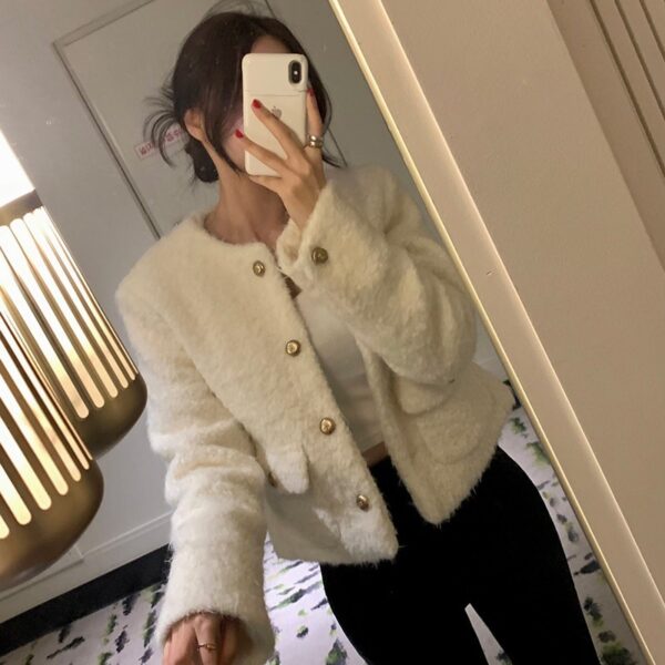 Person wearing a cozy white cardigan taking a mirror selfie.
