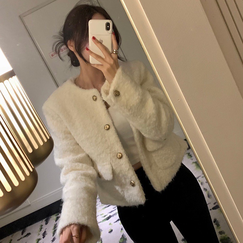 Person wearing a cozy white cardigan taking a mirror selfie.