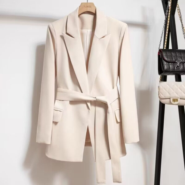 Beige blazer with belt on hanger.