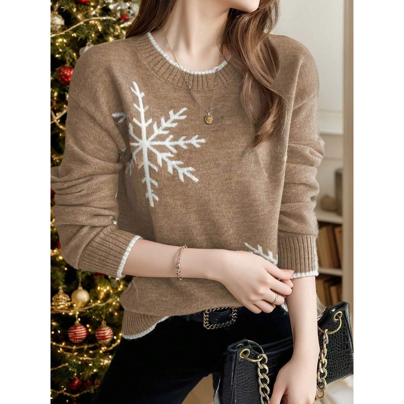 Woman wearing snowflake sweater near Christmas tree.