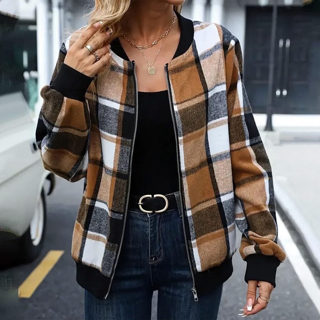 Woman wearing plaid jacket and jeans outdoors.