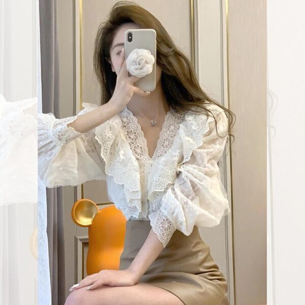Woman taking mirror selfie in lace blouse.