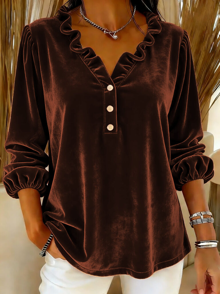 Woman wearing brown velvet blouse, white pants.