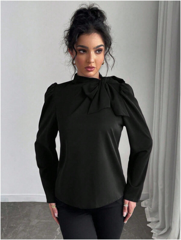 Woman wearing a stylish black blouse indoors.