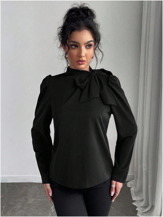 Woman in black blouse with bow detail.
