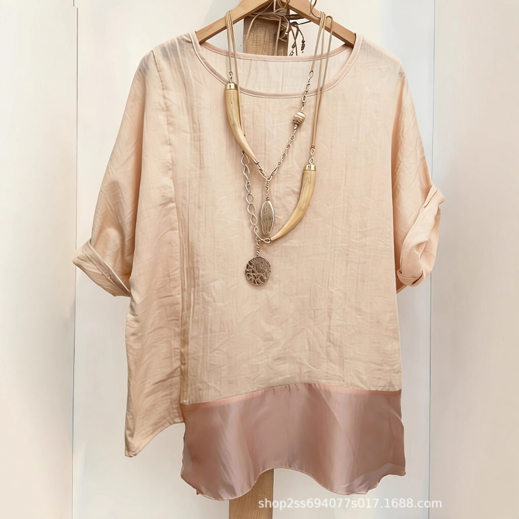 Beige blouse with necklace on hanger.