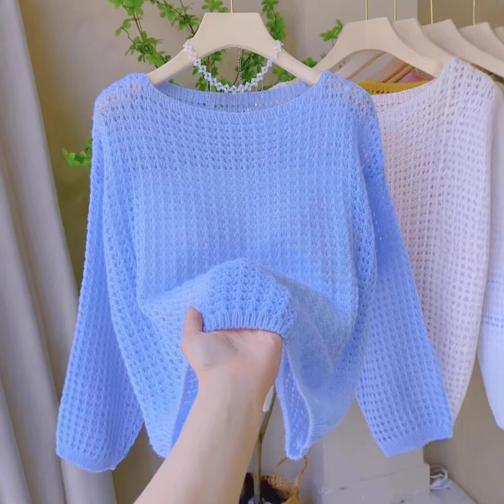 Hand holding blue knit sweater on hanger.