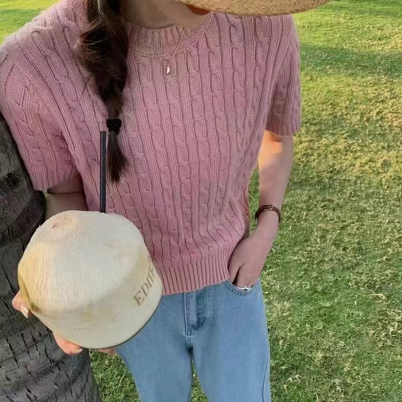 Person holding coconut, wearing pink sweater.