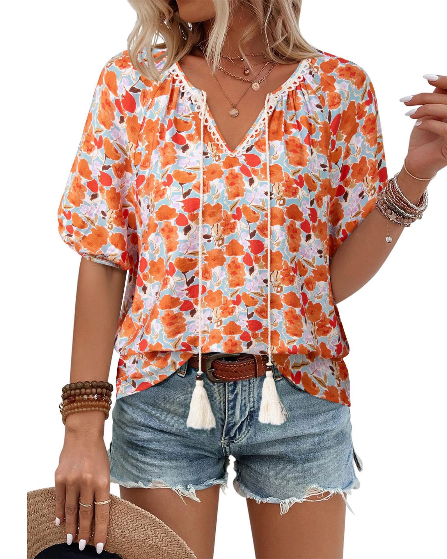 Woman wearing floral blouse and denim shorts.