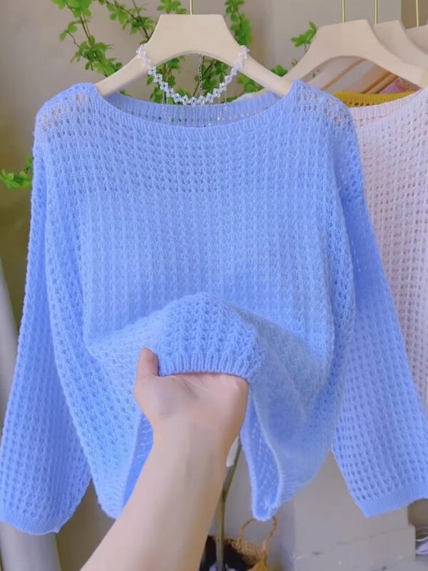 Hand holding a light blue knit sweater.