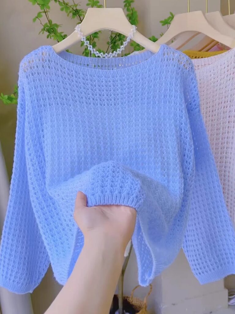 Hand holding a light blue knit sweater.