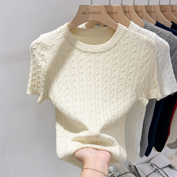 Beige cable-knit sweater on wooden hanger.