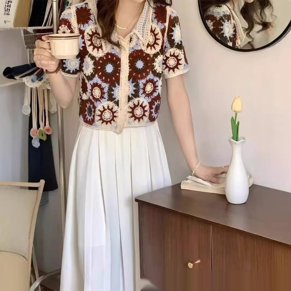Woman holding coffee cup in floral top.