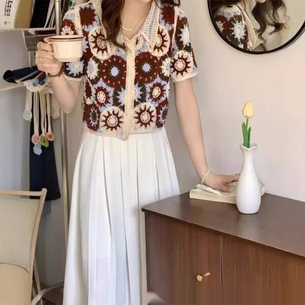 Woman holding coffee cup in floral top.