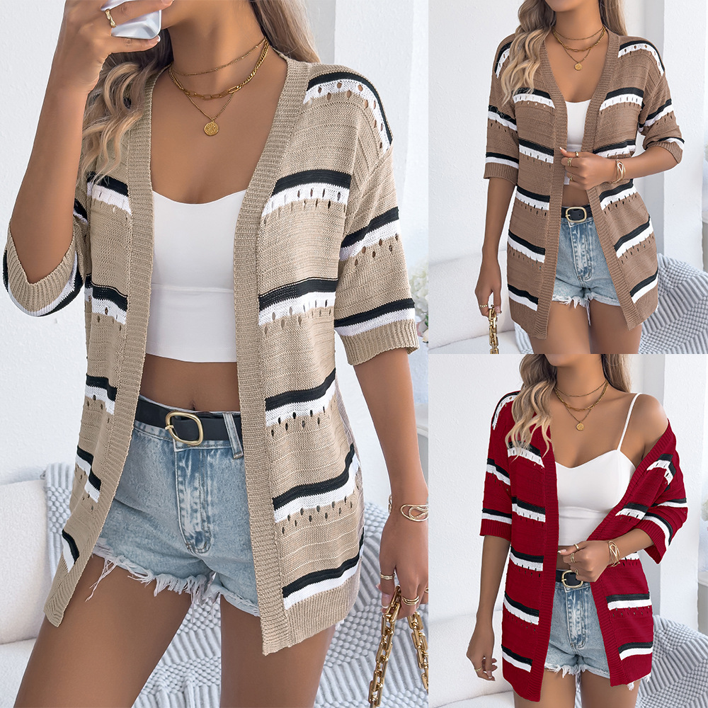 Woman wearing striped cardigan and denim shorts.