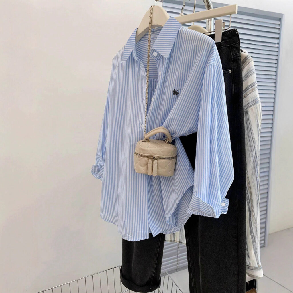 Striped shirt with small beige handbag displayed.