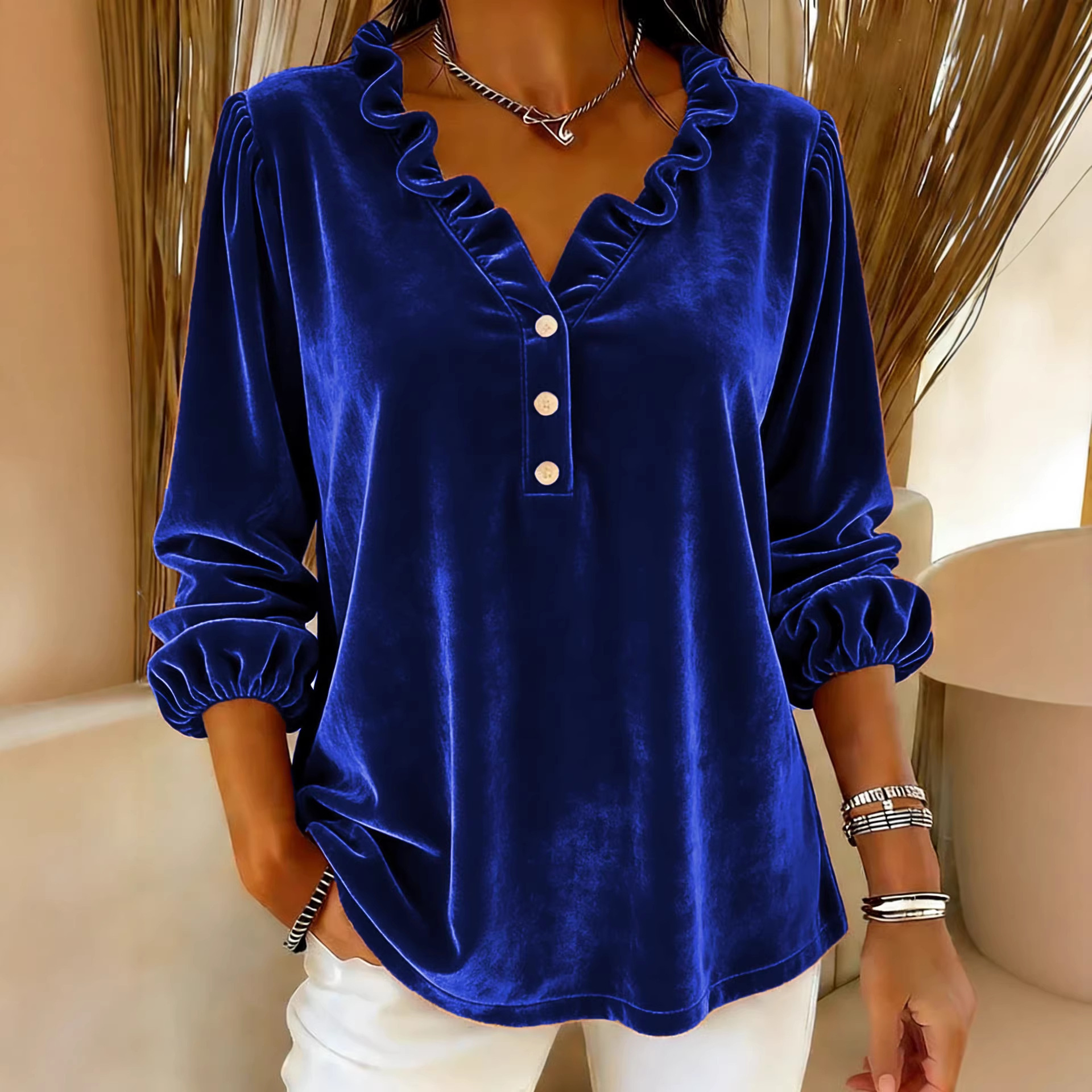 Woman in blue velvet blouse, indoors.