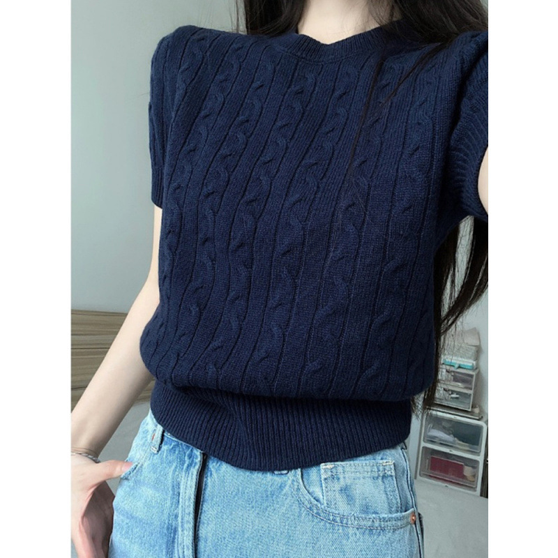 Person wearing a navy cable knit sweater.