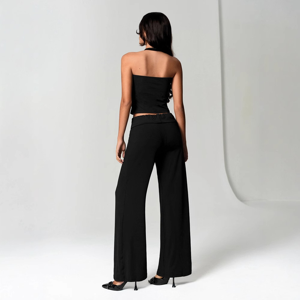 Woman in black outfit, standing, facing away.
