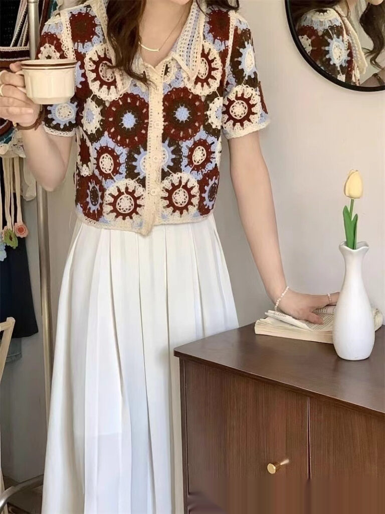 Woman holding cup, wearing floral-patterned blouse.
