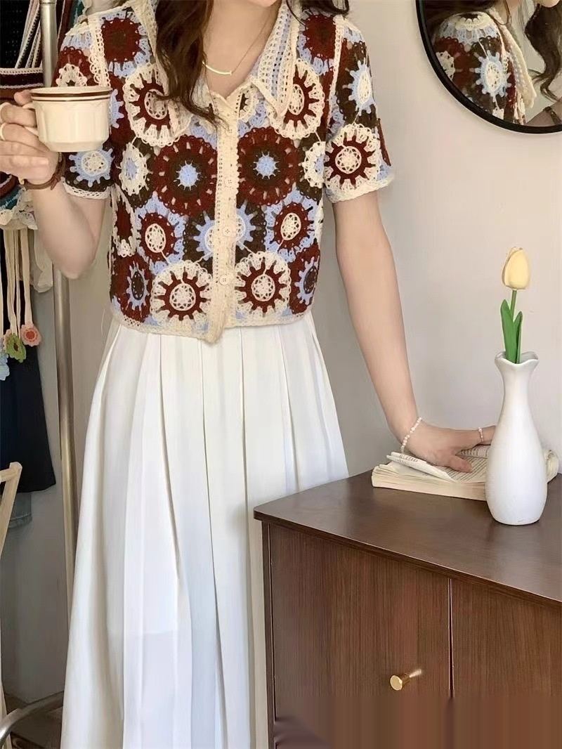 Woman holding cup, wearing floral-patterned blouse.